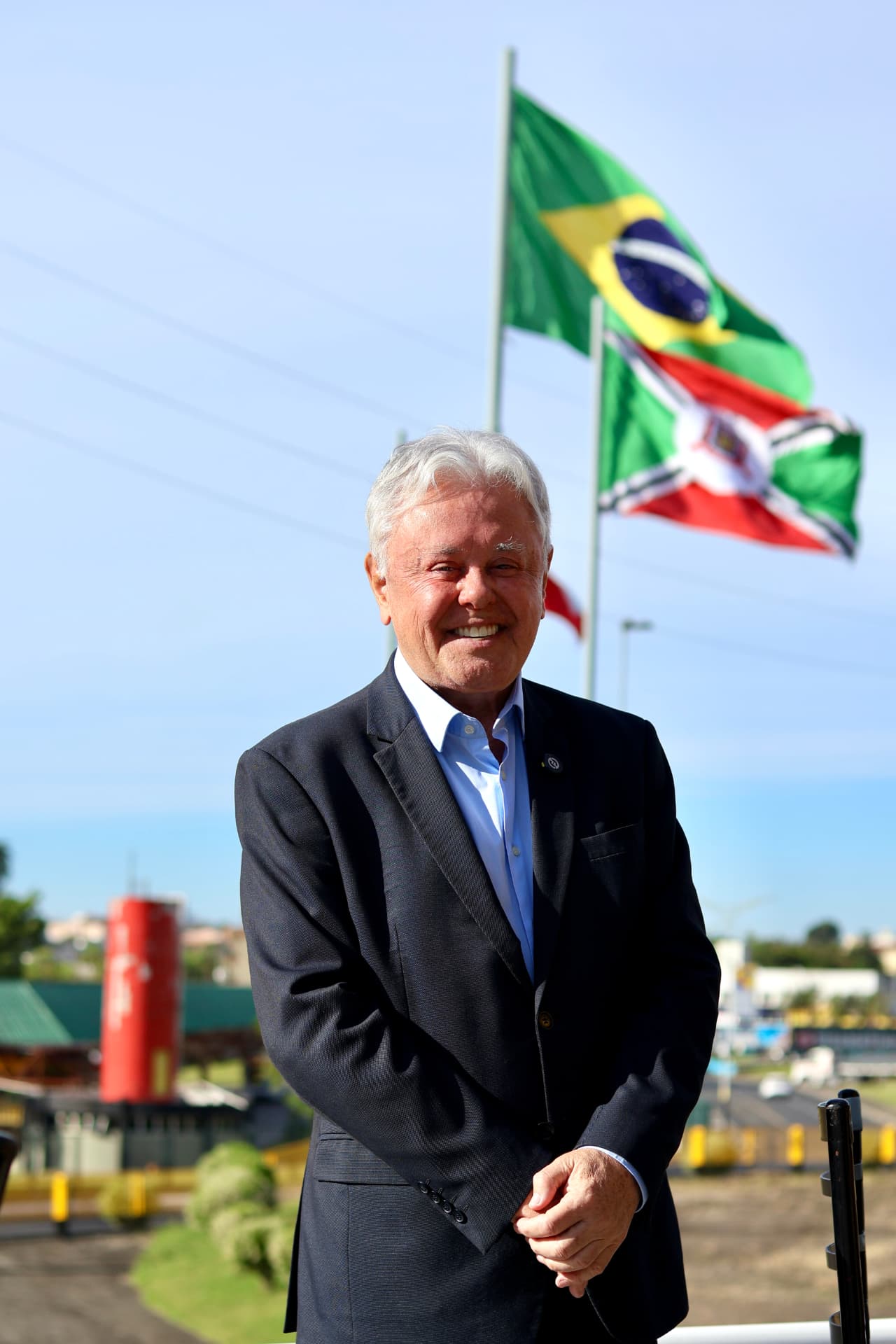 Paulo Alceu em frente às bandeiras do Brasil e de Santa Catarina
